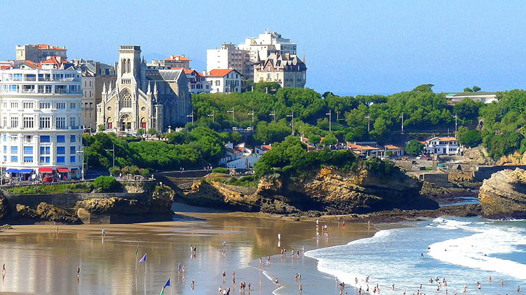 A panoramic view of the beach at Biarritz, France, and the coastal skyline of the city above the beach.