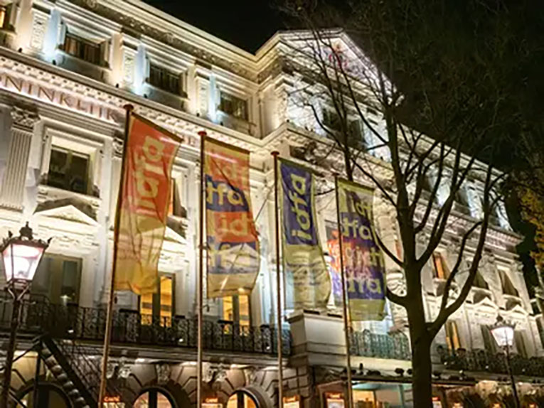 The exterior of an elegant building in Amsterdam with four IDFA banners waving in front of it.