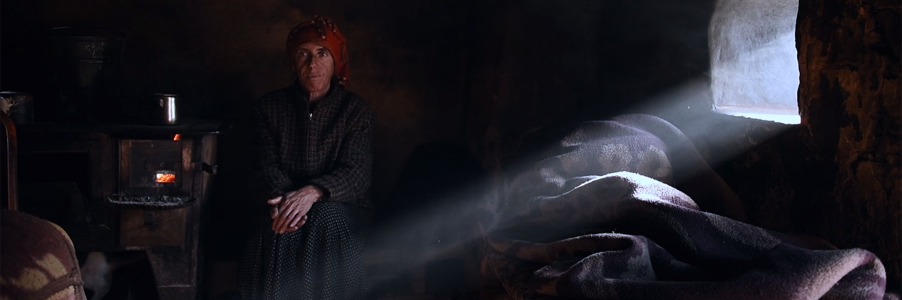 A woman sits in a dark room.