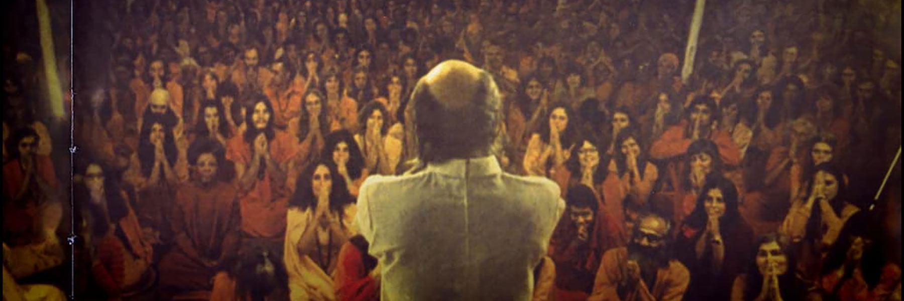 A man speaking on a stage to a large crowd.